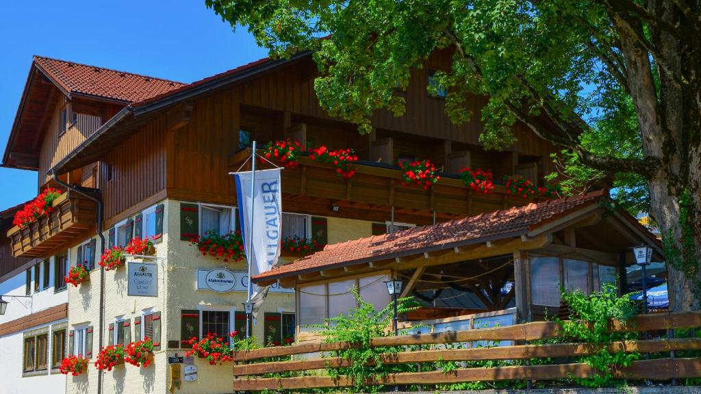 ein Gebäude mit roten Blumen auf dem Balkon in der Unterkunft Hotel Gasthof Rose in Oy-Mittelberg