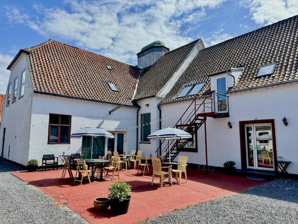 a building with a patio with tables and umbrellas at Groland Bornholm B&B in Pedersker