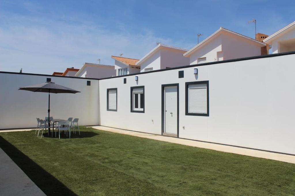 a white house with a lawn and an umbrella at Siorica AG Low Cost in Matalascañas