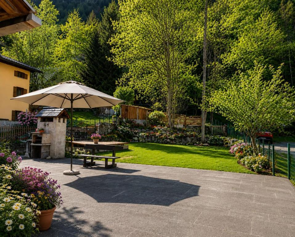 a picnic table with an umbrella in a garden at Casa di Maen in Valtournenche
