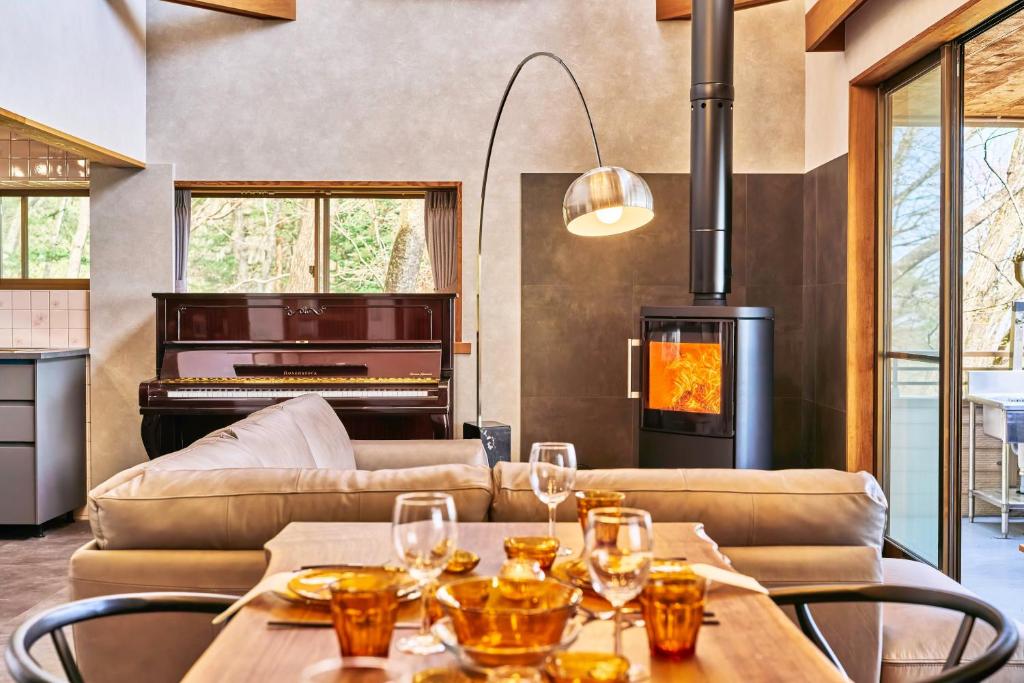 a living room with a piano and a table with wine glasses at NASU Fir Tree in Nasu