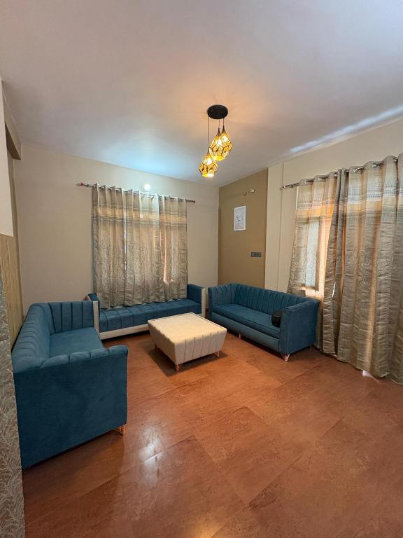 a living room with two blue couches and a table at Oliway Homestay in Lohaghāt