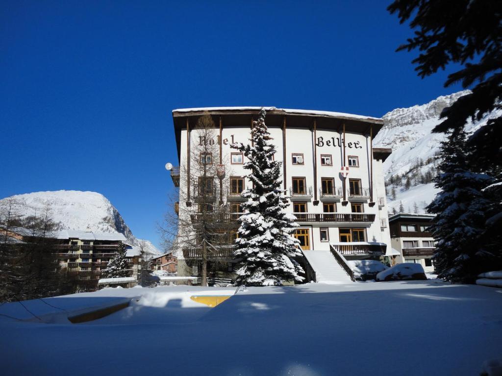 a building in the snow with a tree in front of it at Hôtel Bellier in Val dʼIsère