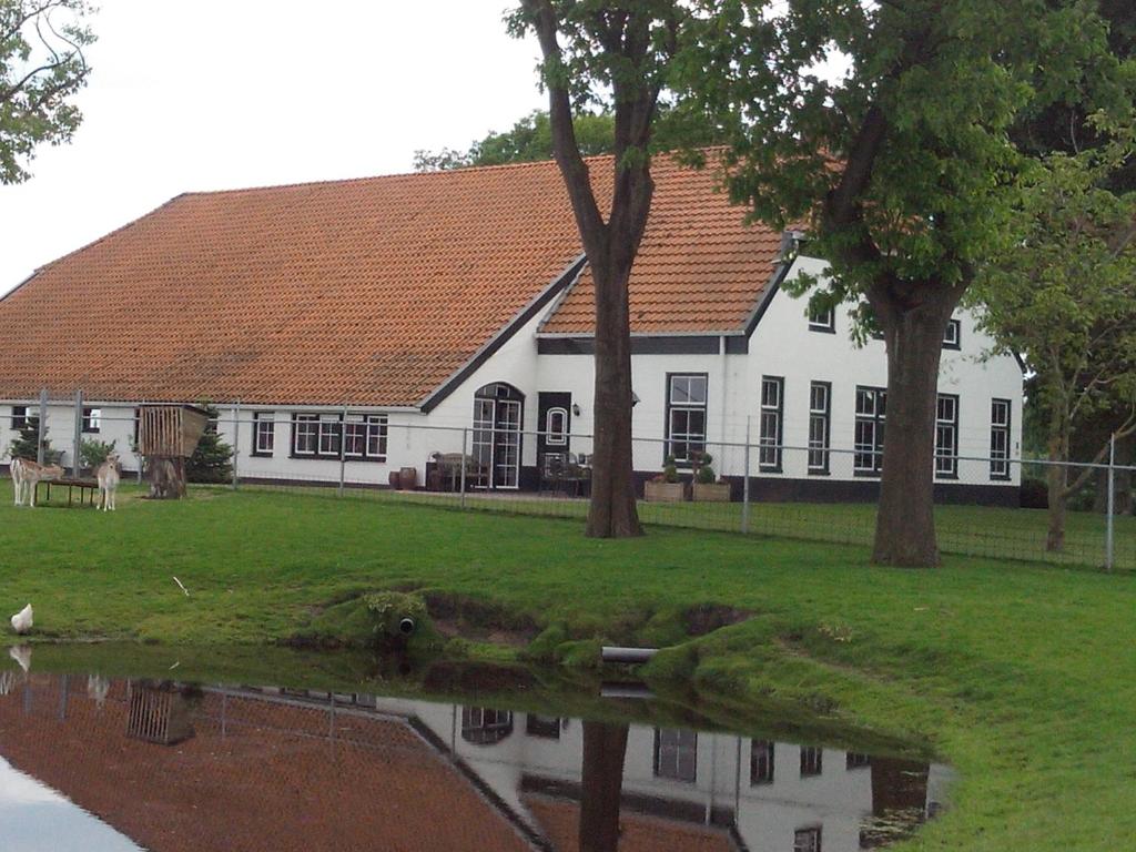 uma grande casa branca com árvores em frente em bed en breakfast westerwolde em Sellingen