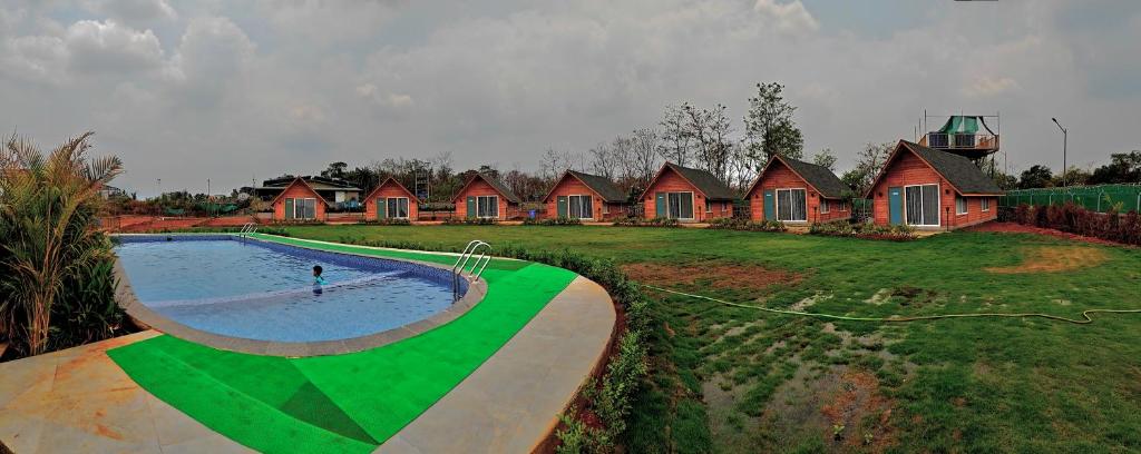 a person in a pool in a yard with a house at Karibu Karjat Resort in Karjat