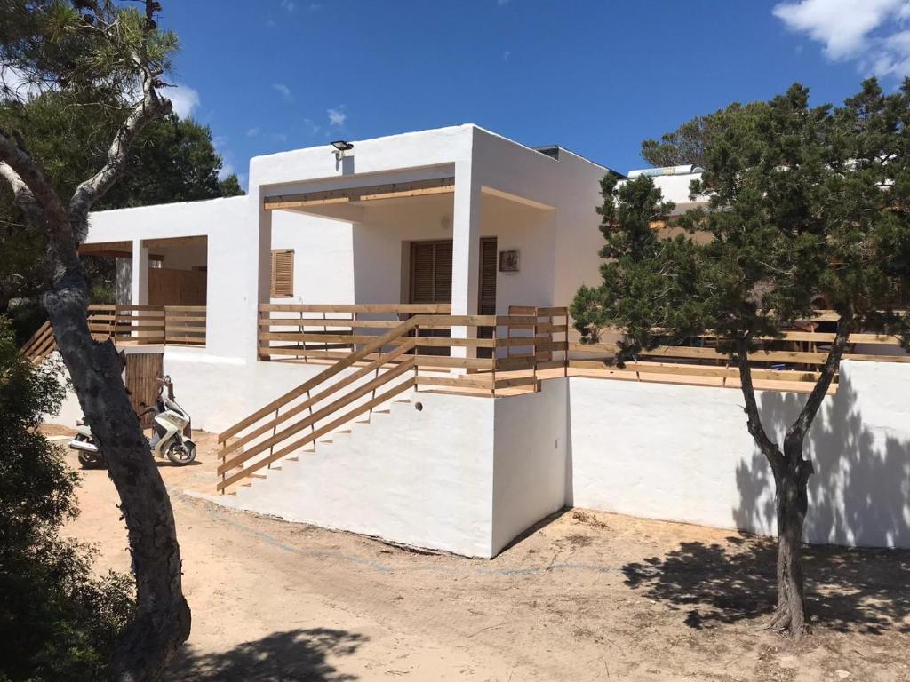 a white house with a tree in front of it at Apartamentos Es Cupina in La Mola