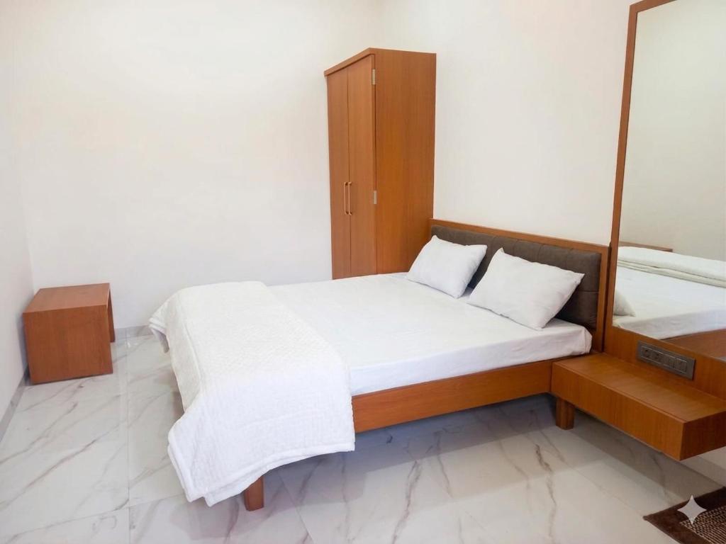 ein kleines Schlafzimmer mit einem Bett und einem Spiegel in der Unterkunft Hotel Bliss County in Dhule