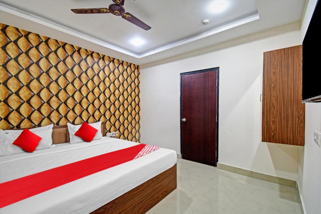 a bedroom with a bed with red pillows at Hotel O ASHIRBAD PALACE in Urāli