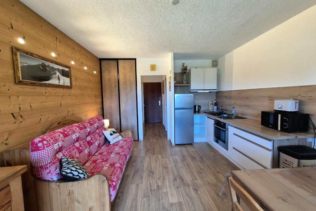 a living room with a couch and a kitchen at Chaleureux studio au pied des pistes - Le refuge in Les Déserts