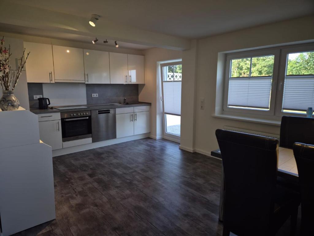 an empty kitchen with white cabinets and a table at Sonnenterrasse in Hörup