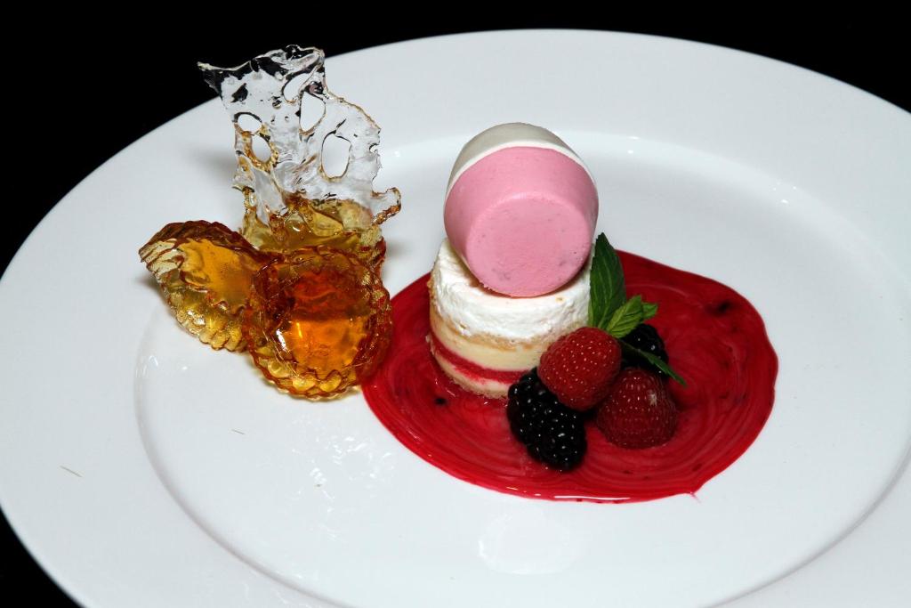 a white plate with a dessert with strawberries and ice cream at Swiss Flora Royal Hotel Riyadh in Riyadh