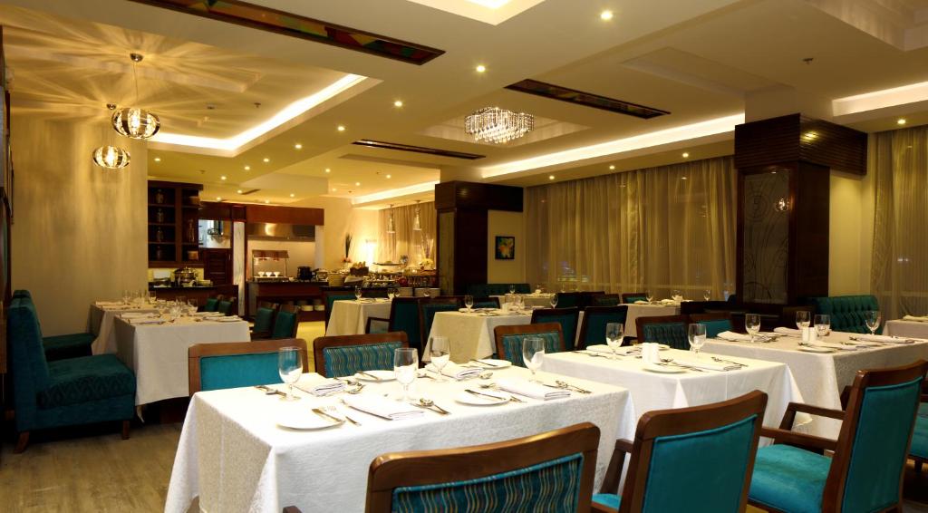 a dining room with white tables and chairs at Swiss Flora Royal Hotel Riyadh in Riyadh