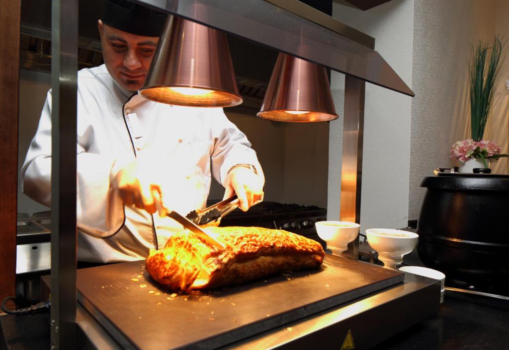 a chef preparing a piece of food in a kitchen at Swiss Flora Royal Hotel Riyadh in Riyadh