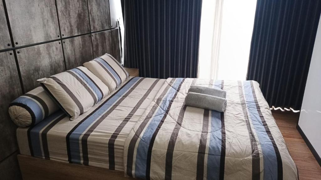 a bedroom with a bed with a striped blanket and pillows at Ruby Apartment #47 in Kejayan