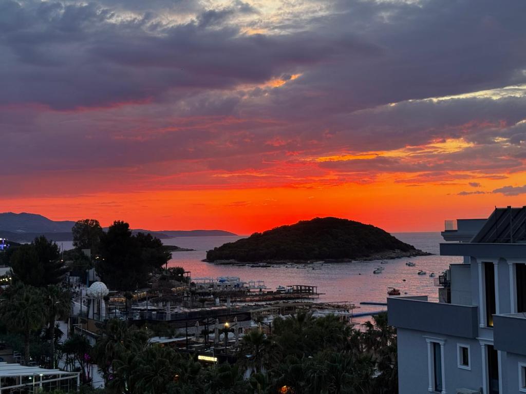 a sunset over a body of water with a small island at Poseidon Hotel Ksamil in Ksamil