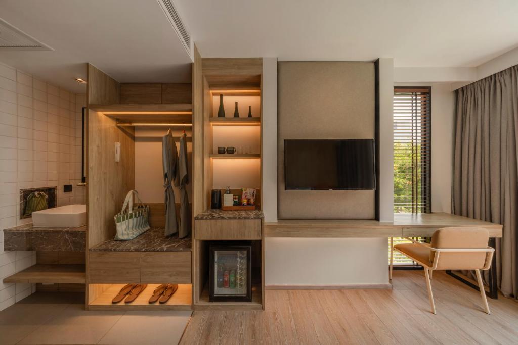 A compact guest room showing its open wardrobe, minibar, television and desk beside the bed.
