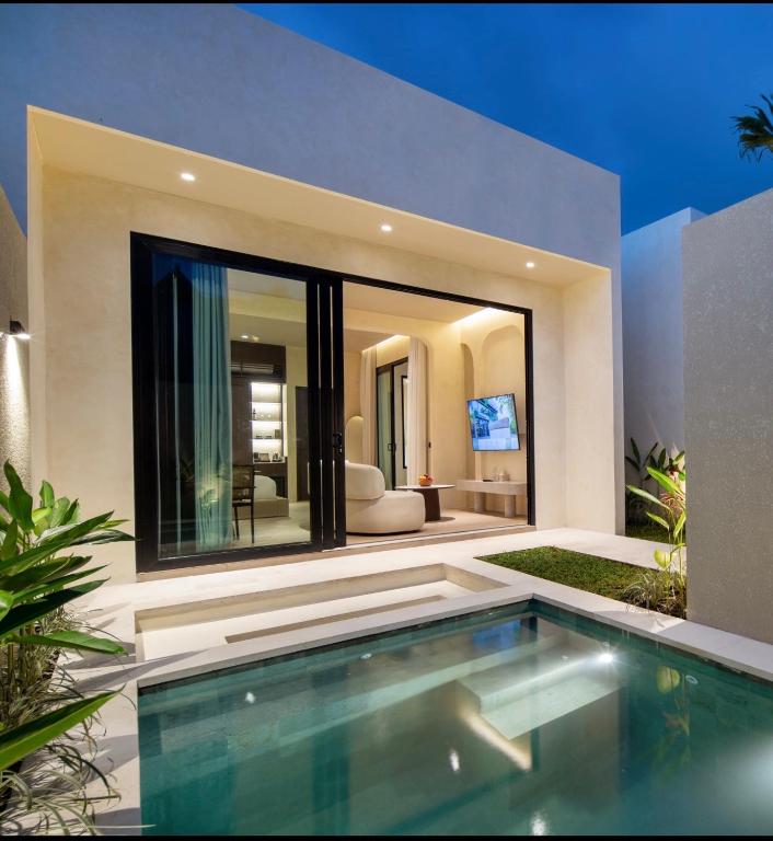 a swimming pool in front of a house at The Lario Collection - A Wellness Resort in Seminyak