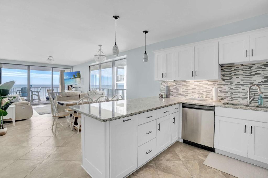 a kitchen with white cabinets and a dining room at Corner on Romar 706 in Orange Beach