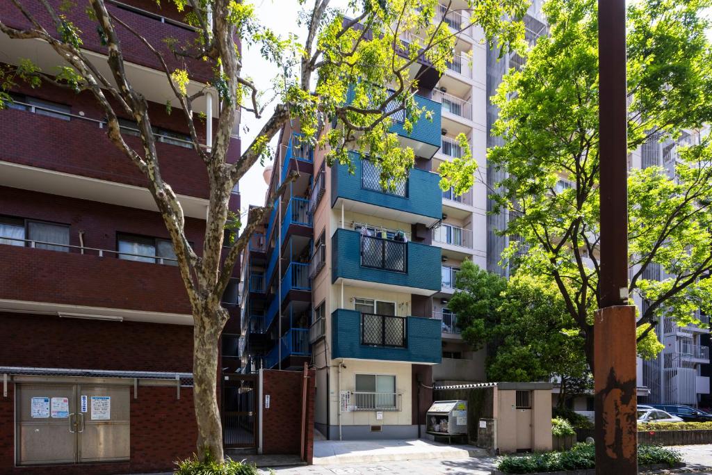 an apartment building with blue balconies and a tree at 第2舞鶴ハイツ in Fukuoka