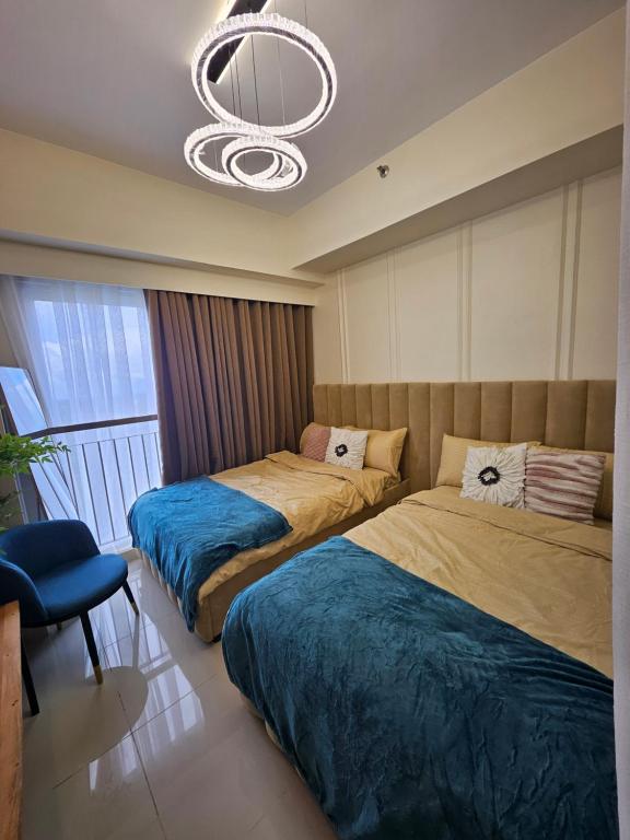 a bedroom with two beds and a chandelier at Alder Wind Staycations Tagaytay in Kaybagal
