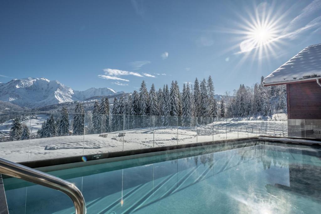 a swimming pool with a view of snow covered mountains at Les Roches du Mont Blanc - Résidence & Spa in Combloux
