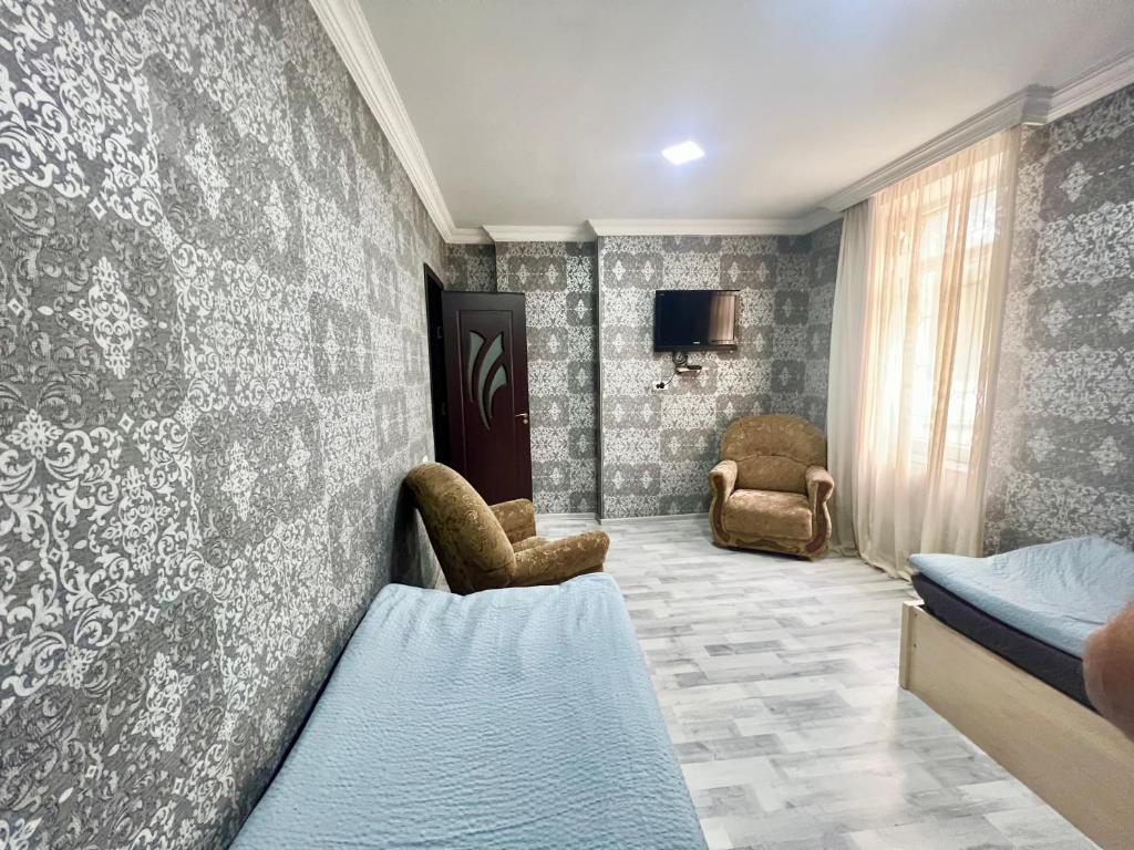 a room with two beds and two chairs and a tv at Ruslan Hotel 1 in Poti