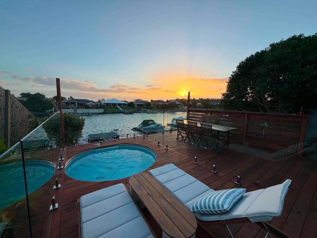 a deck with a swimming pool and a table and chairs at Pet Friendly - Plunge Pool Canal Sunset View - Private Jetty in Bongaree