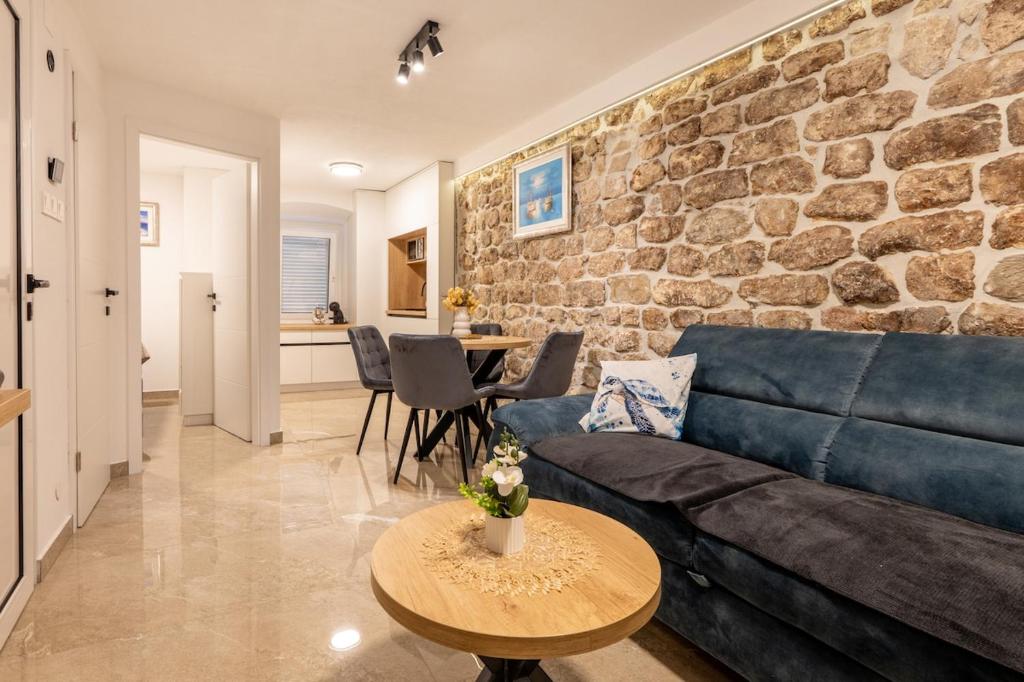 a living room with a blue couch and a stone wall at Apartmani Žunić in Pag