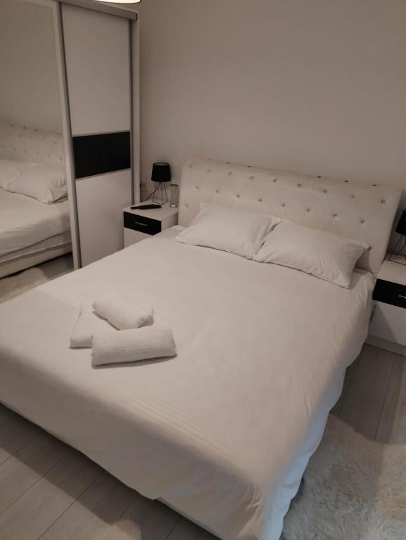 a large white bed with two folded towels on it at Bella apartman in Mladenovac