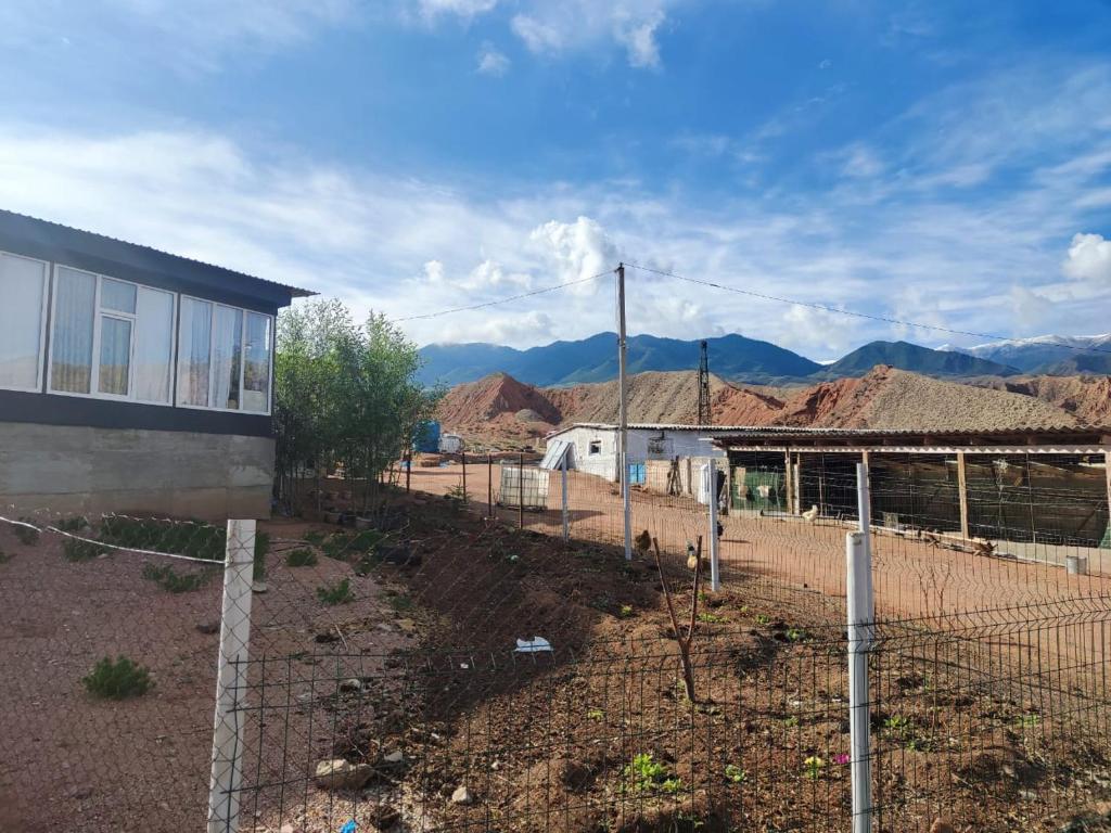 a fence in front of a building with mountains in the background at Эко Жайлоо in Kaji-Say