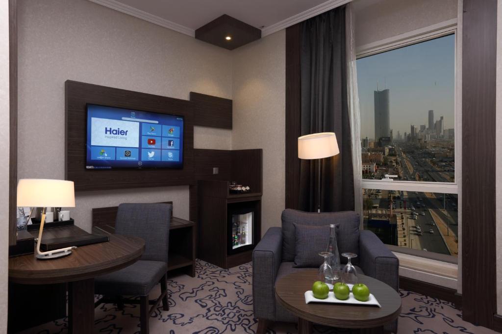 a hotel room with a tv and a living room at Swiss Flora Royal Hotel Riyadh in Riyadh