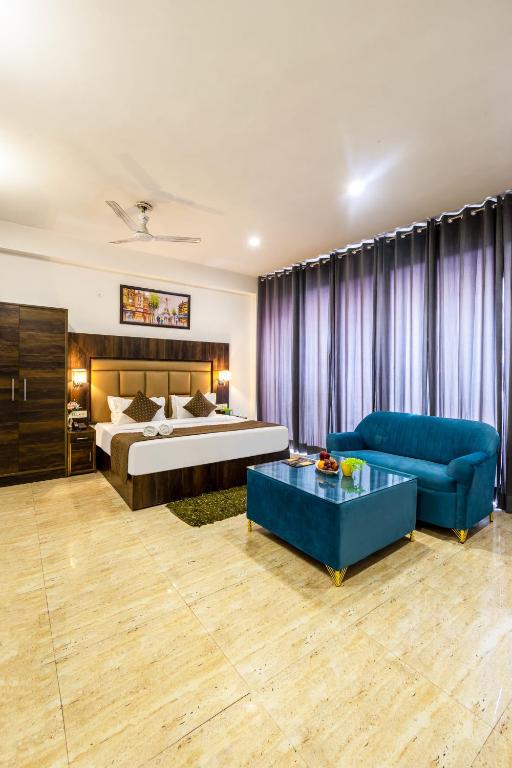 a bedroom with a bed and a blue couch at Hotel Apple Tree - Near Mahipalpur Market in New Delhi