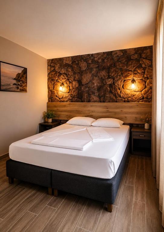 a bedroom with a bed with a stone wall at Assos Plus in Ayvacık