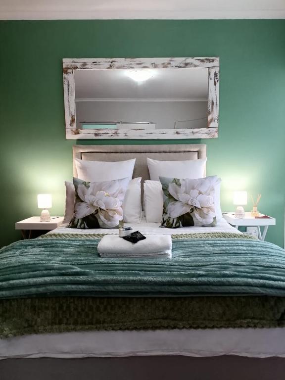 a bedroom with a large bed with a green comforter at 47atKabega in Gqeberha