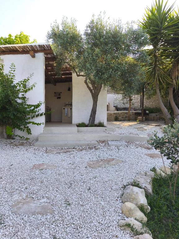 a yard with a building and trees and gravel at Camping Fiori di Noto in Noto