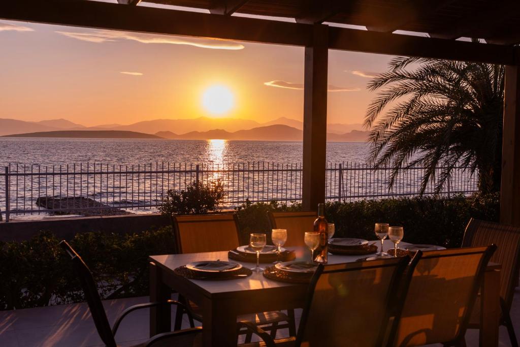 a table with a view of the ocean at sunset at Villa Isabelle on the beach in Paralía Iríon