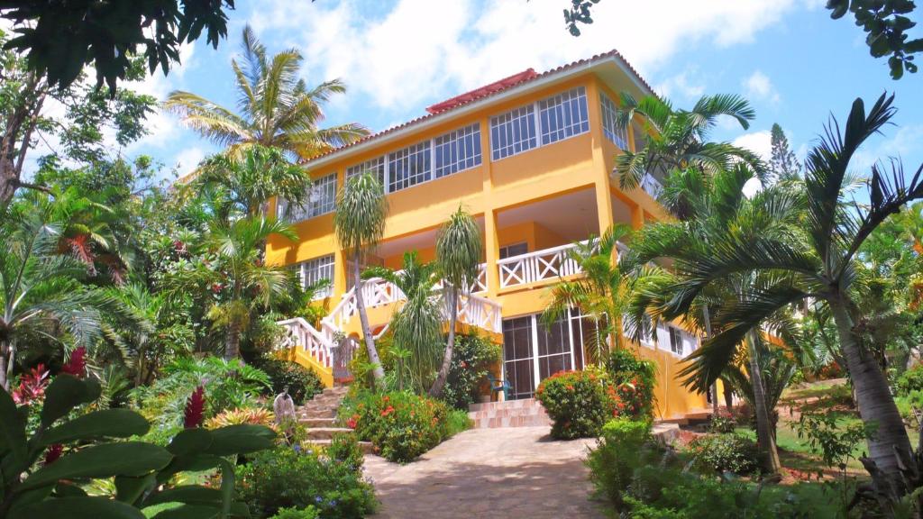 a yellow building with palm trees in front of it at Casa Tropical in San Felipe de Puerto Plata