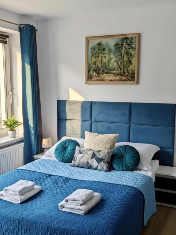 a blue bed with towels on top of it at Apartamenty Bliza in Ostrowo
