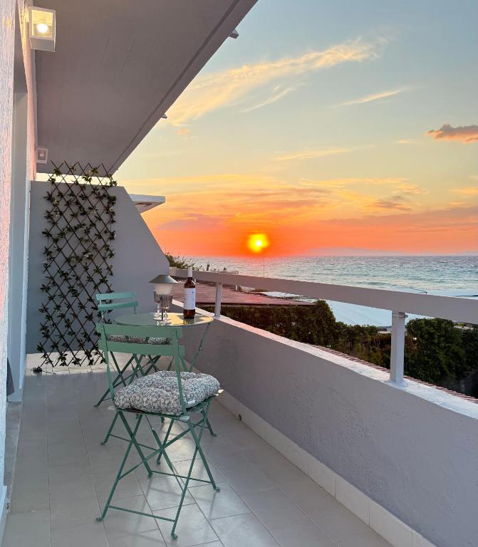 a table and chair on a balcony with a sunset at Beachfront Luxury Studio with Panoramic Sea View in Ialysos