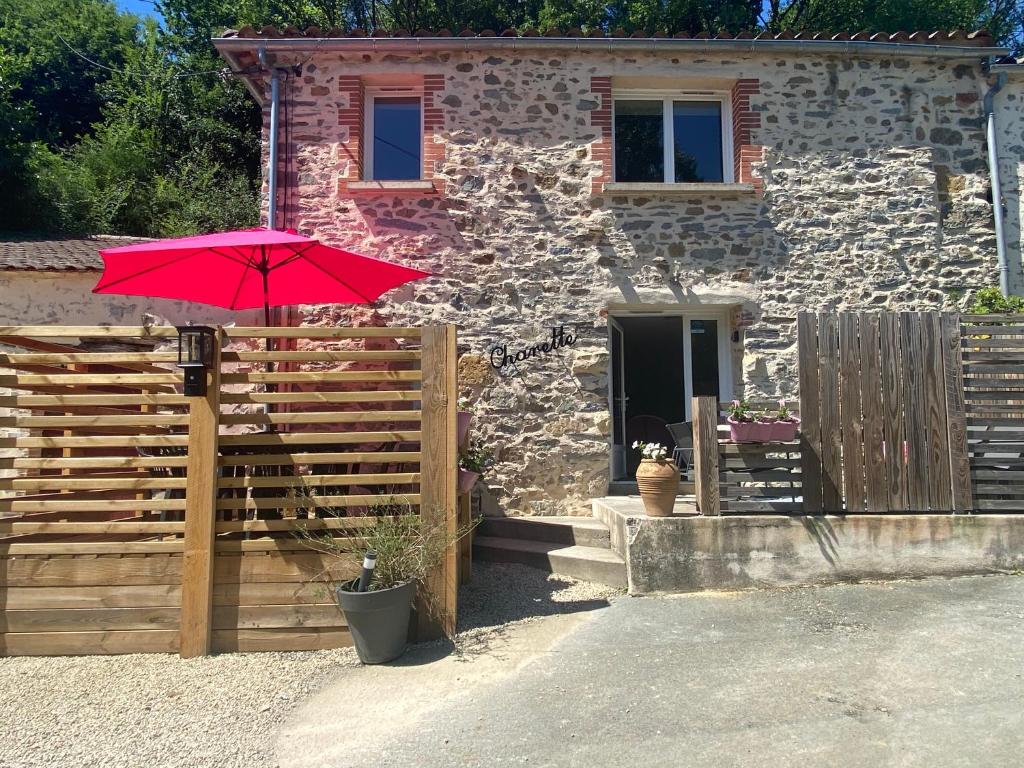 a red umbrella in front of a stone house at Les rives du Lay gîte Charette in Le Boupère
