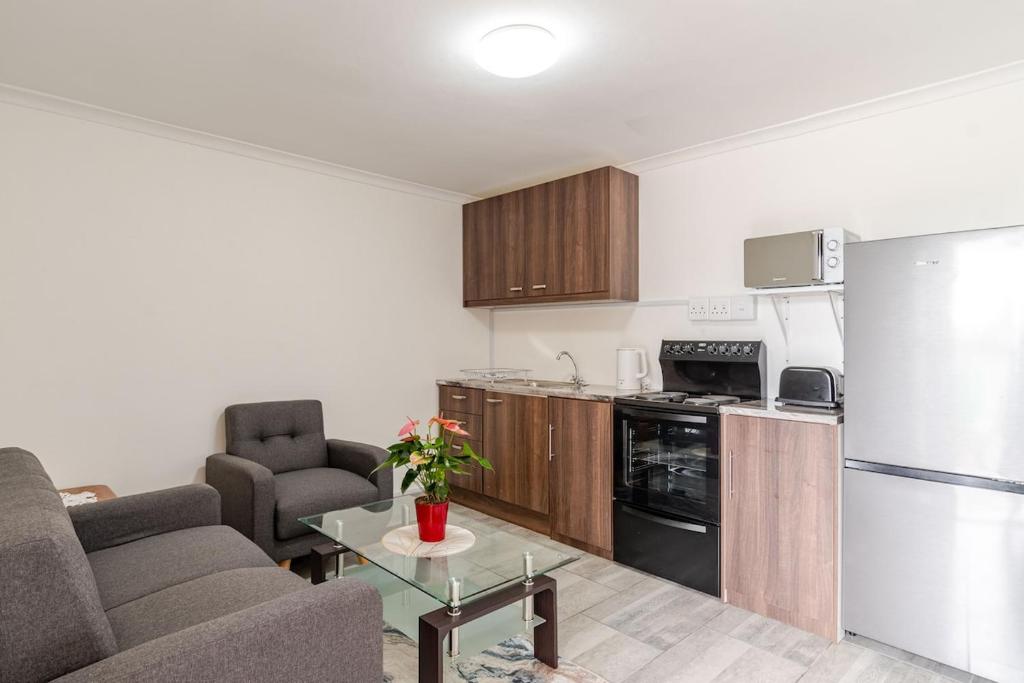 a living room with a couch and a kitchen at Sintha guest house in Kraaifontein