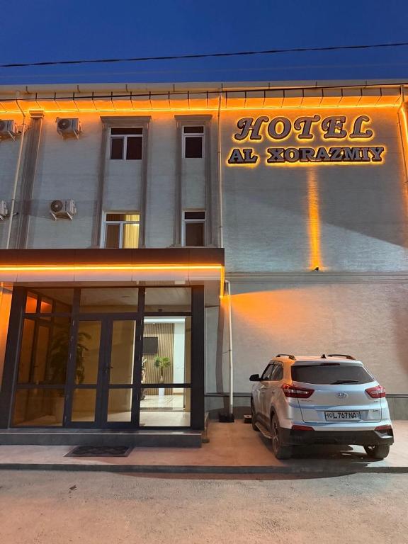 a white car parked in front of a building at Al-Xorazmiy Hotel in Urganch