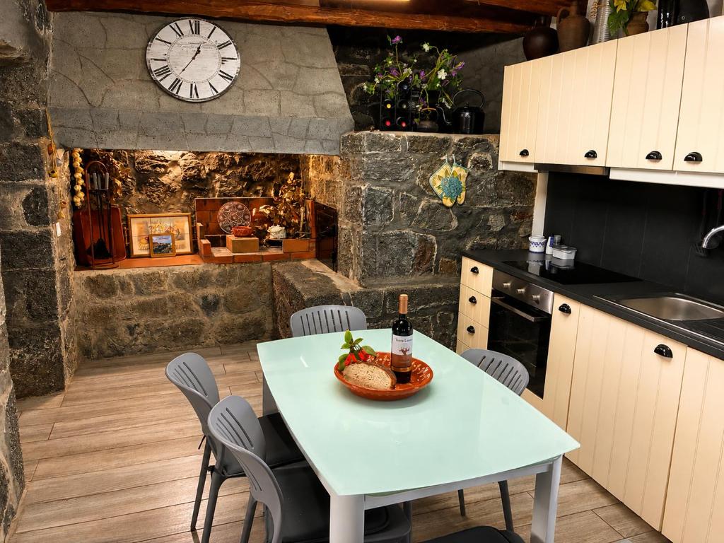 a kitchen with a table and a clock on the wall at Casinha de Pedra in Cais do Pico
