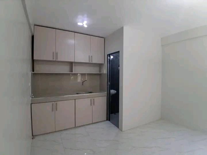 eine Küche mit weißen Schränken und einem schwarzen Kühlschrank in der Unterkunft Merlyn Donque in Cainta