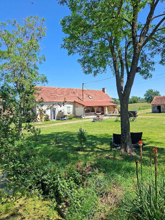 a house with a tree in front of a yard at chambres d'hôtes Domaine les Grands Pérons in Hérisson