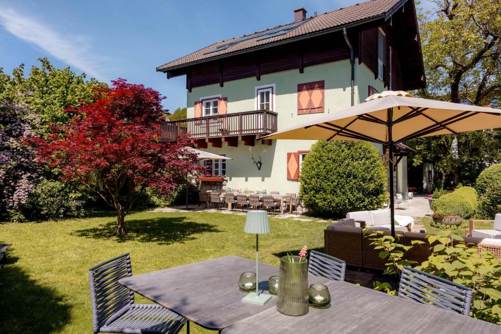 a table with an umbrella in front of a house at Villa Stella all famous ski areas around us, 15 minutes to salzburg, mountainview in Golling an der Salzach