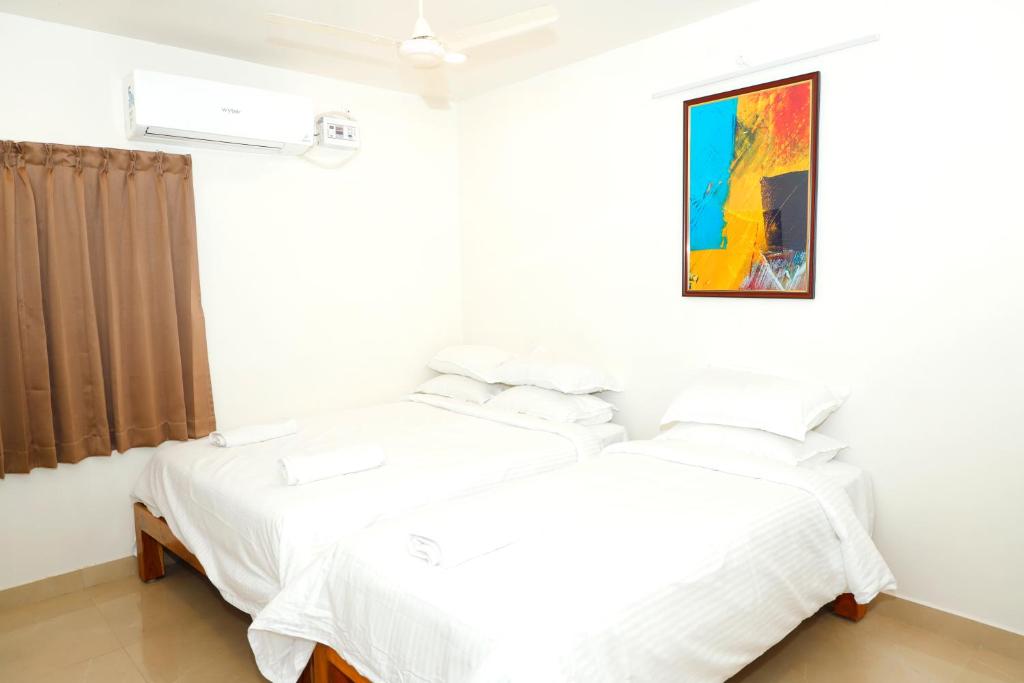 a bedroom with two beds and a painting on the wall at Shri Valli Rooms in Tiruvannāmalai