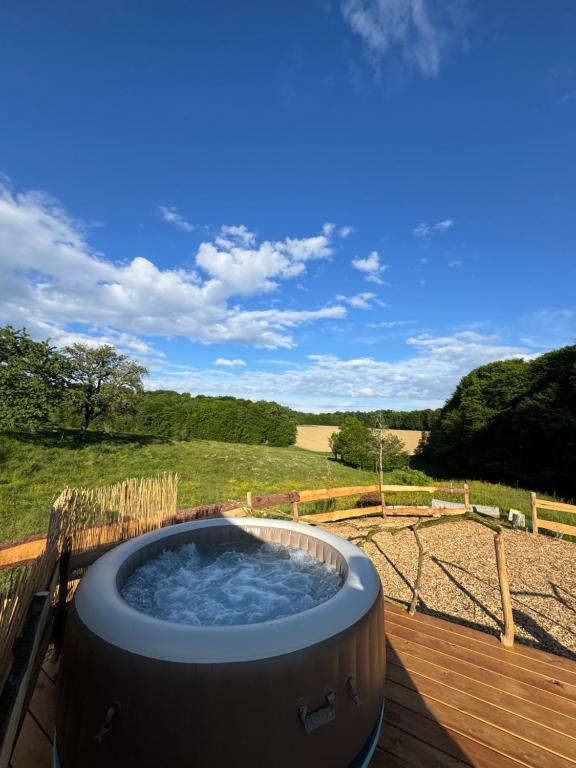 a hot tub on a deck with a view of a field at Hupkac Glamping retreat in Vodranci