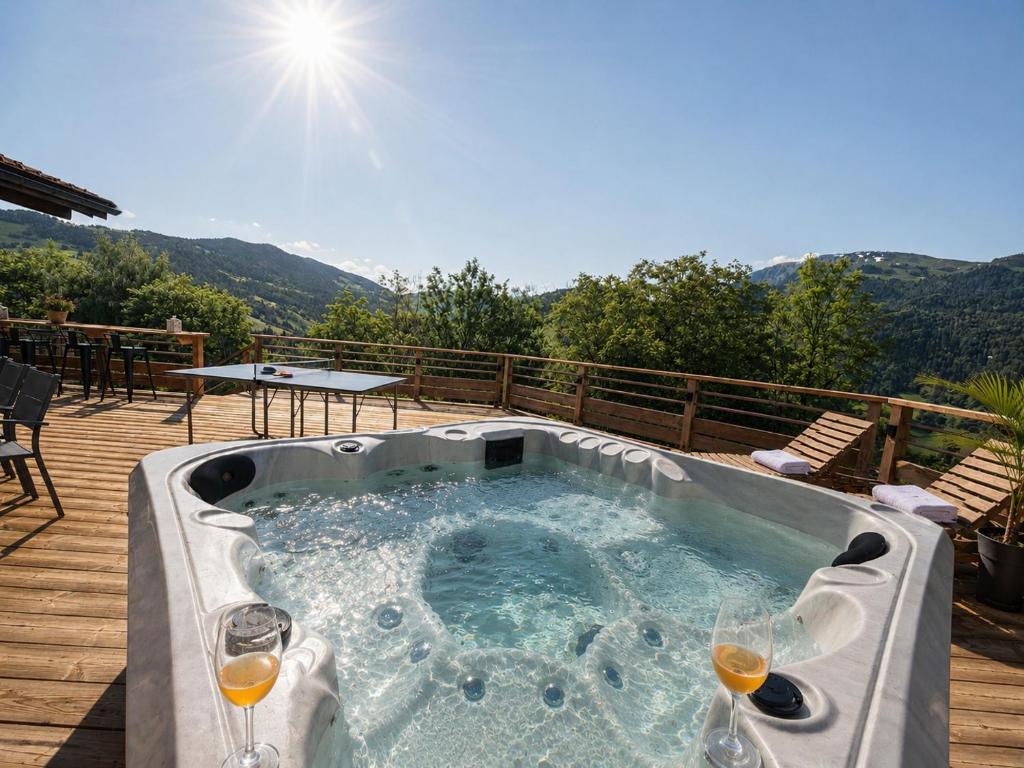 a hot tub on a deck with two glasses of wine at Charming family Chalet for 8 people, with private Hot Tub in Les Clefs