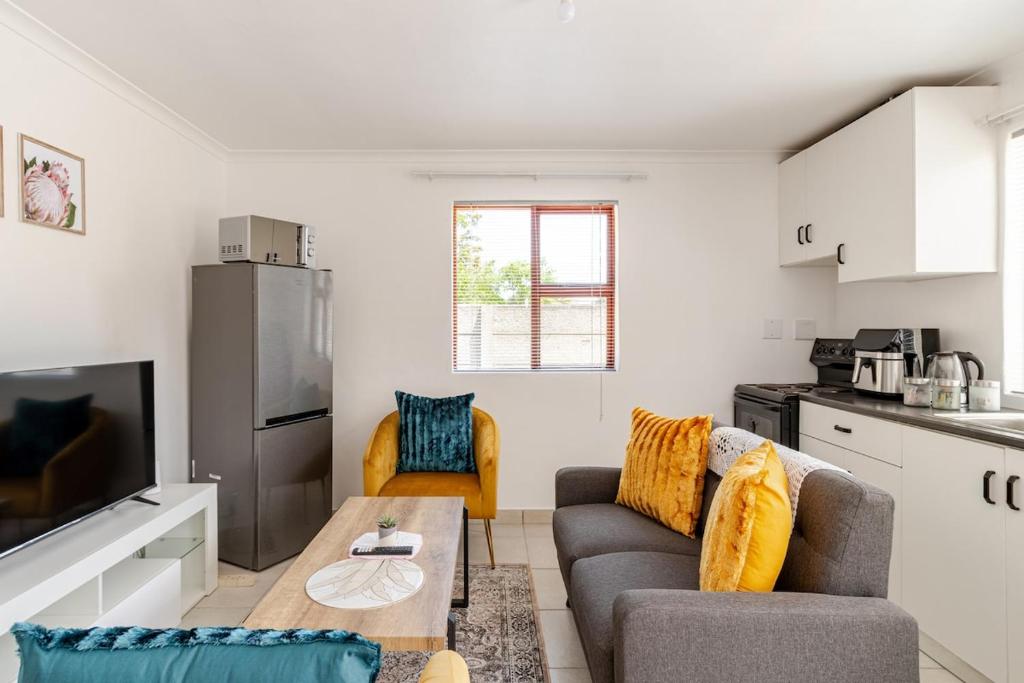 a living room with a couch and a table in a kitchen at Sintha Guesthouse in Kraaifontein